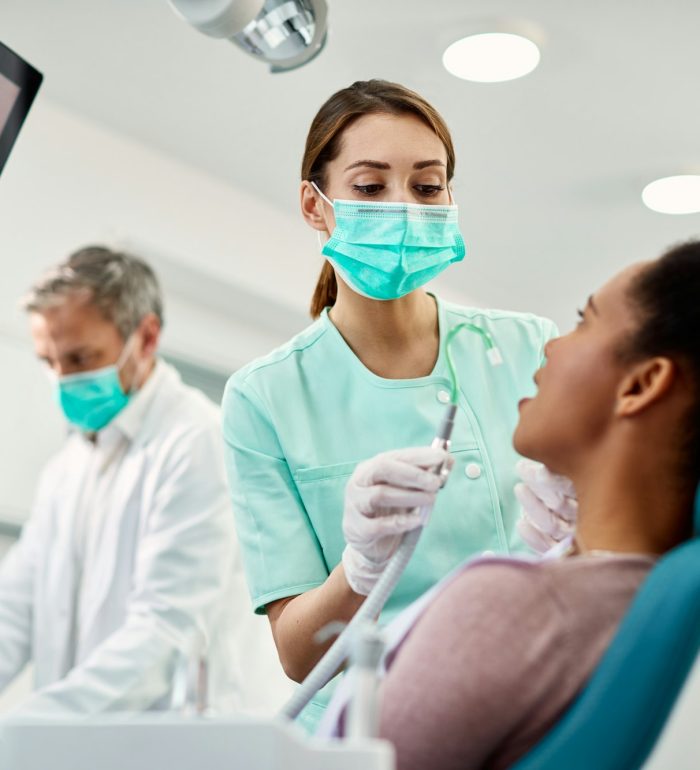 Young nurse preparing patient for dental procedure at dentist’s office. Young nurse preparing patient for dental procedure at dentist's office.